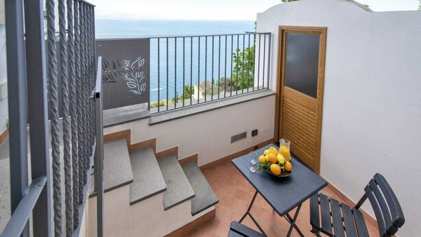 Un balcon avec une table, des chaises et un panier de fruits.