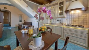 Une cuisine moderne équipée d’une cuisinière à gaz, de meubles blancs et d’un coin repas avec une table mise pour le petit-déjeuner.