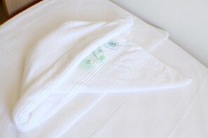 Een keurig opgevouwen witte handdoek met een zichtbaar label, op een witte ondergrond.