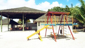 A beachside playground with a swing set and a thatched-roof structure. - Hotel Abrolhos (Nova Viçosa)