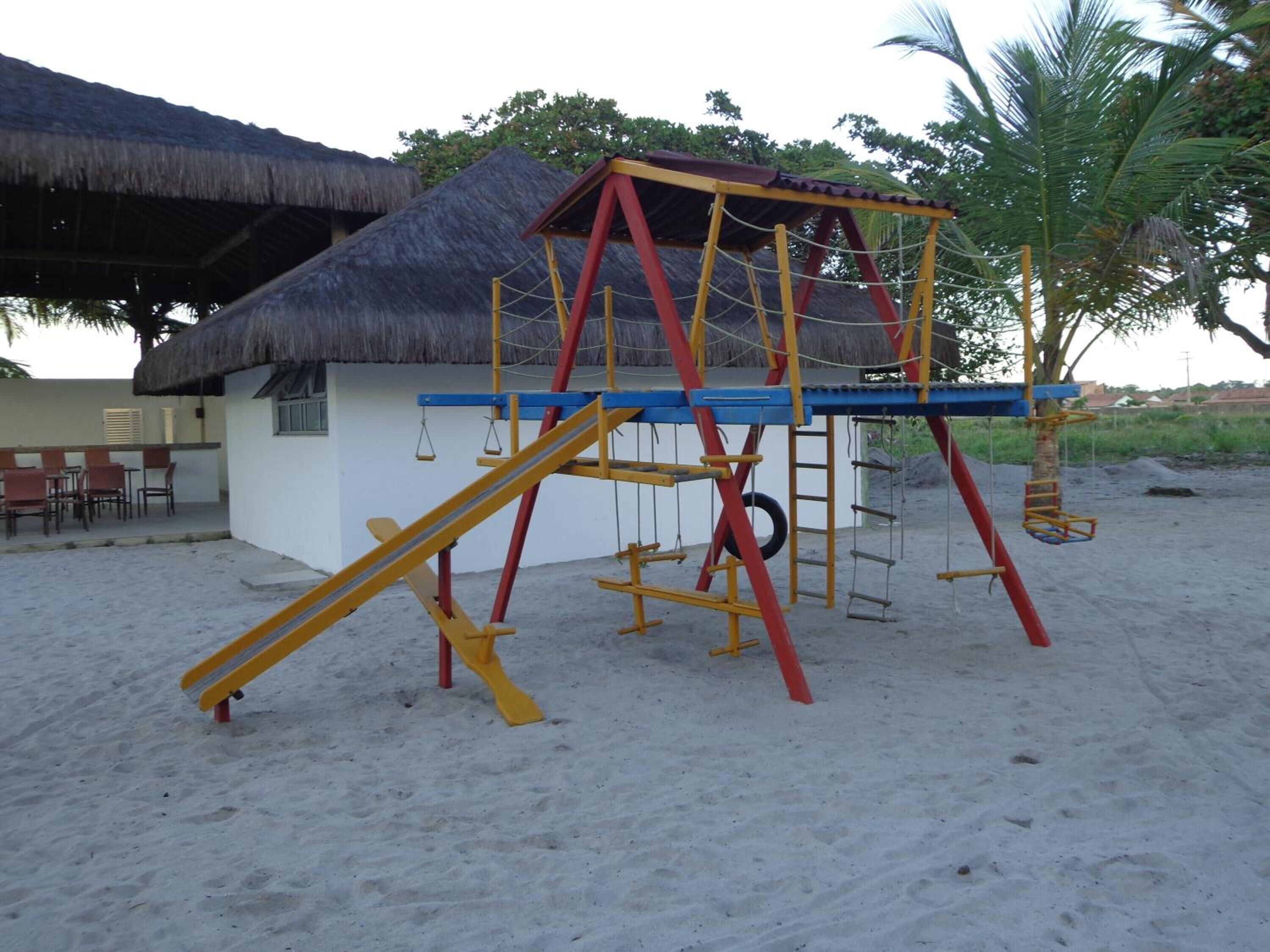 A beachside playground with a swing set and climbing structures.