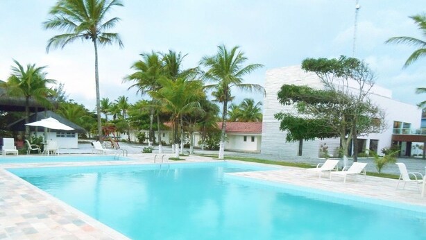 A swimming pool with lounge chairs and palm trees. - Hotel Abrolhos (Nova Viçosa)