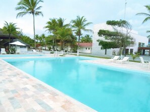 A swimming pool with lounge chairs and palm trees. - Hotel Abrolhos (Nova Viçosa)
