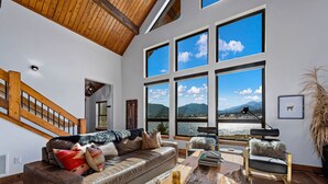 A spacious living room with a large window offering a view of a lake and mountains.