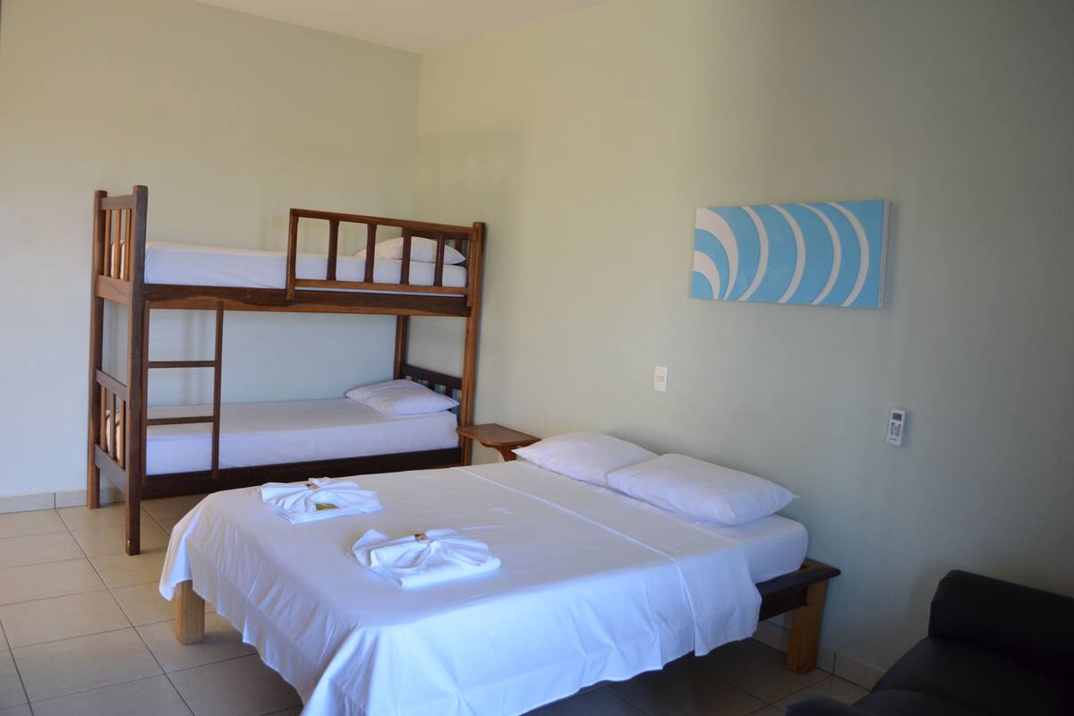 Una habitación con literas, una cama individual y una pequeña mesa.