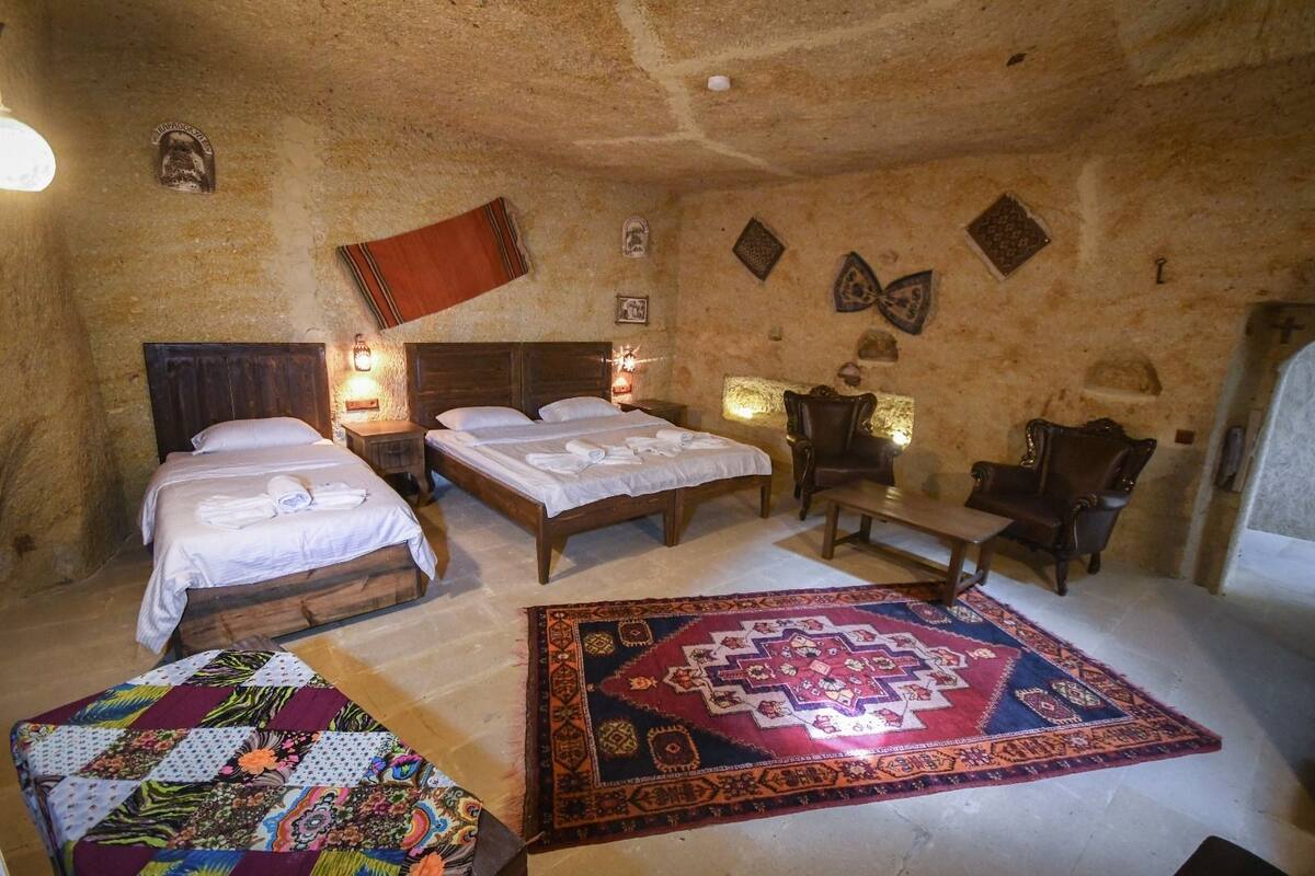 Quarto com uma cama grande, duas camas menores, um banco e um tapete estampado.