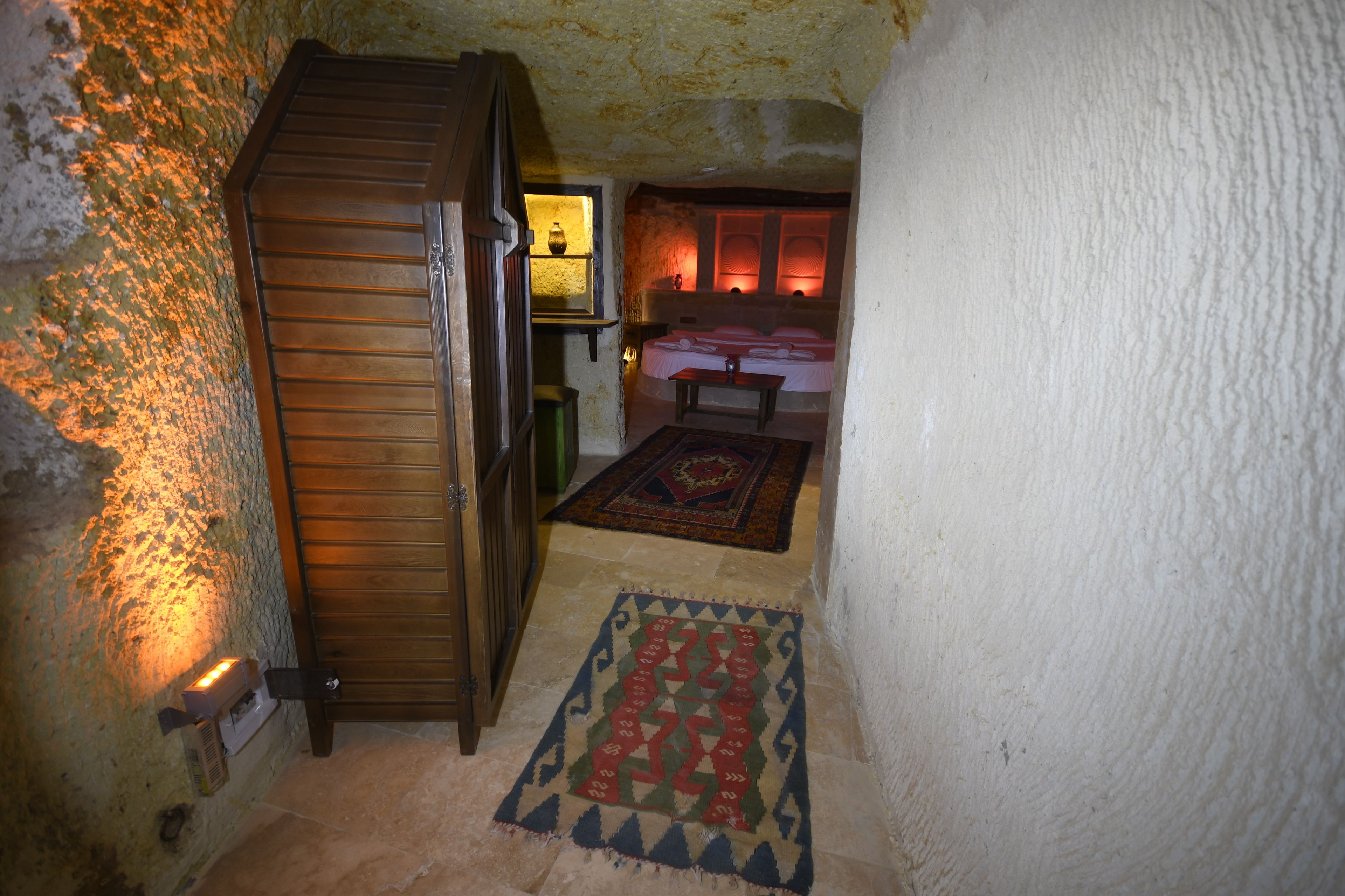 A narrow hallway with a wooden door, a small table, and a patterned rug.