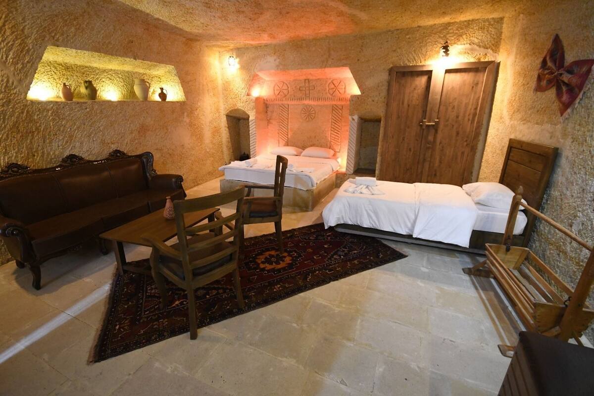 Um quarto aconchegante com sofá, mesa de madeira, cama e uma mesinha com cerâmica.