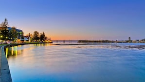 A waterfront area with a bridge, calm water, and buildings in the background. - Hutton Hide Away - East Coast Getaways (The Entrance North)