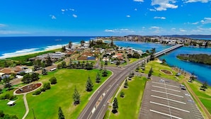 An aerial view of a coastal town with a bridge, roads, and a parking area. - Hutton Hide Away - East Coast Getaways (The Entrance North)