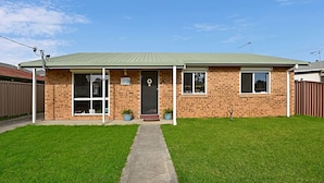 Ein einstöckiges Backsteinhhaus mit Gründach, einer Veranda und einem kleinen Vorgarten.