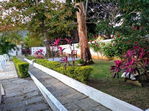 A garden pathway with neatly trimmed hedges and a variety of plants. - Hotel Portal da Praia (São Sebastião)