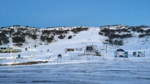Schneebedeckte Landschaft mit einer Seilbahn und einem Gebäude im Hintergrund.