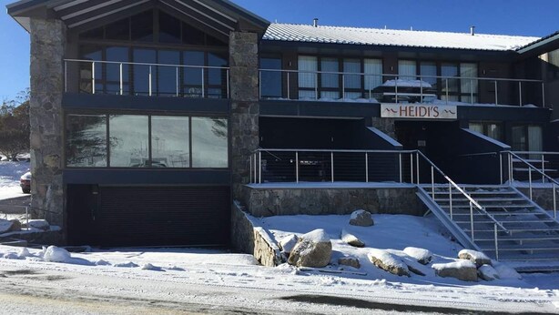 Ein modernes Gebäude mit einer Steinfassade und großen Fenstern, mit einem Schild, auf dem "HEIDI'S" steht.