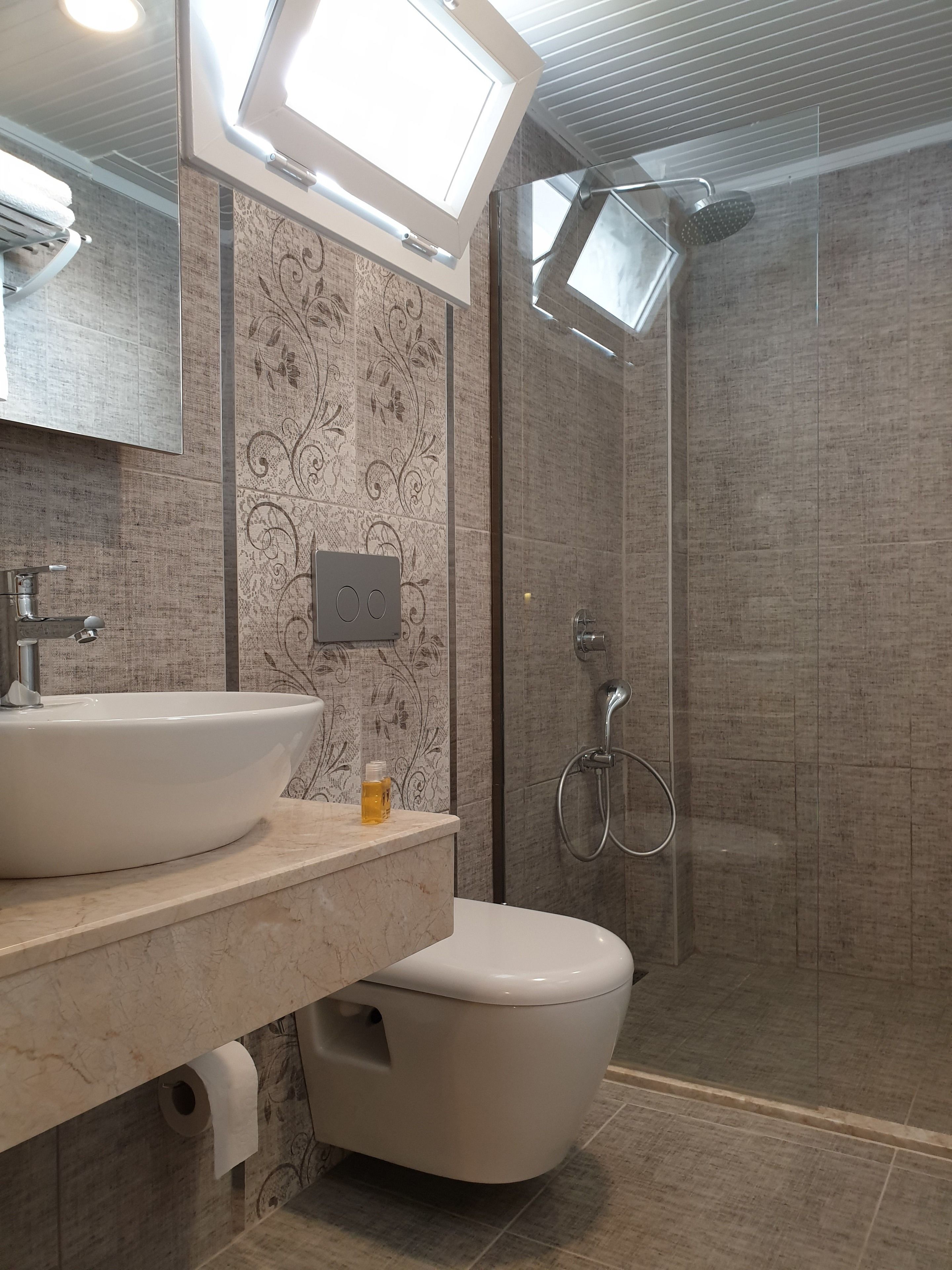 Une salle de bain moderne dotée d’un grand lavabo, de toilettes et d’un espace douche.