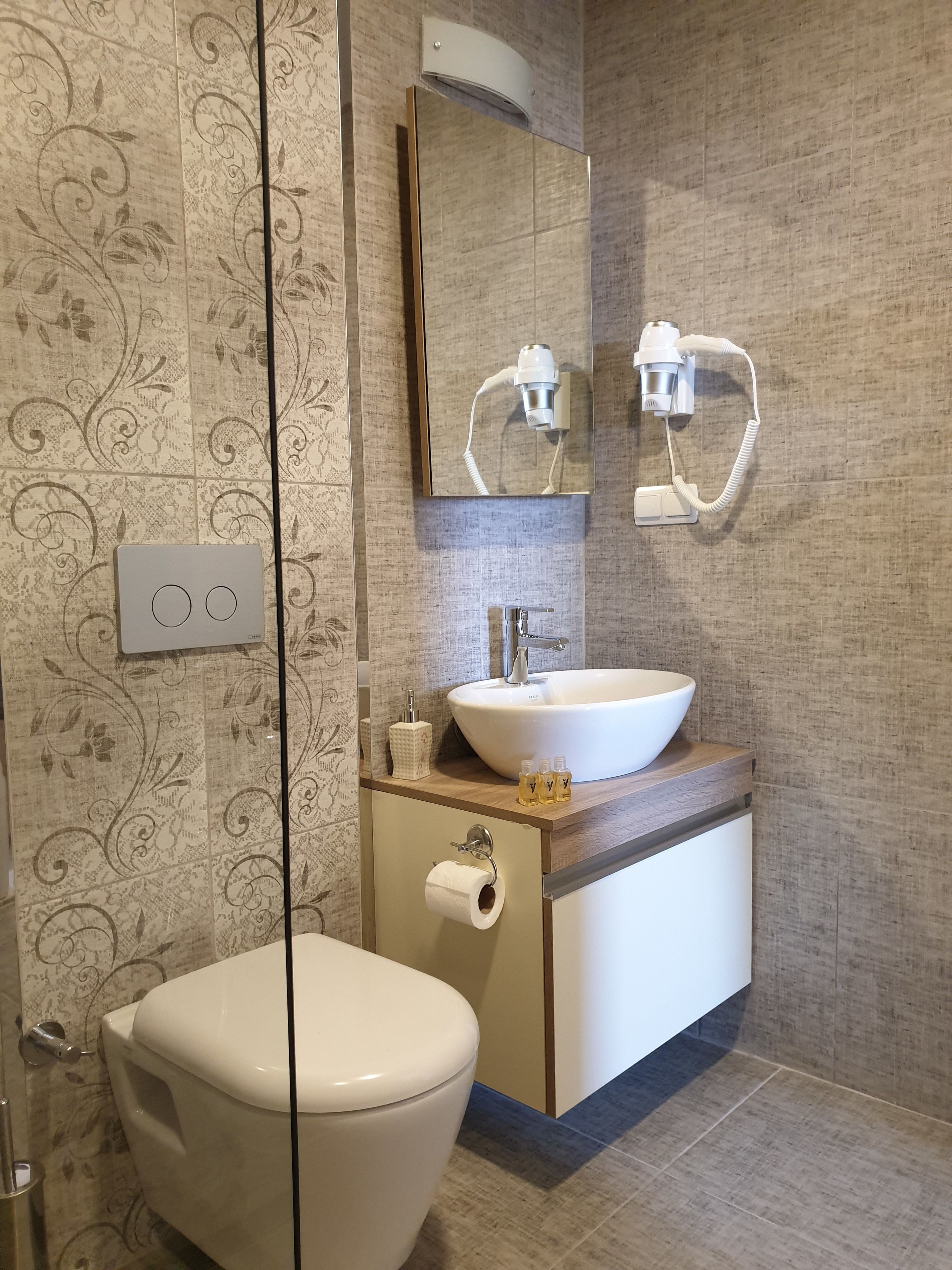 A modern bathroom with a toilet, sink, and mirror.
