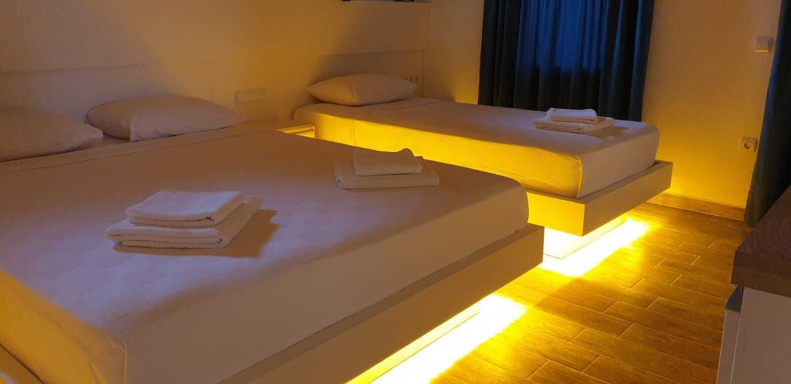 A hotel room with two beds, each with neatly folded towels.