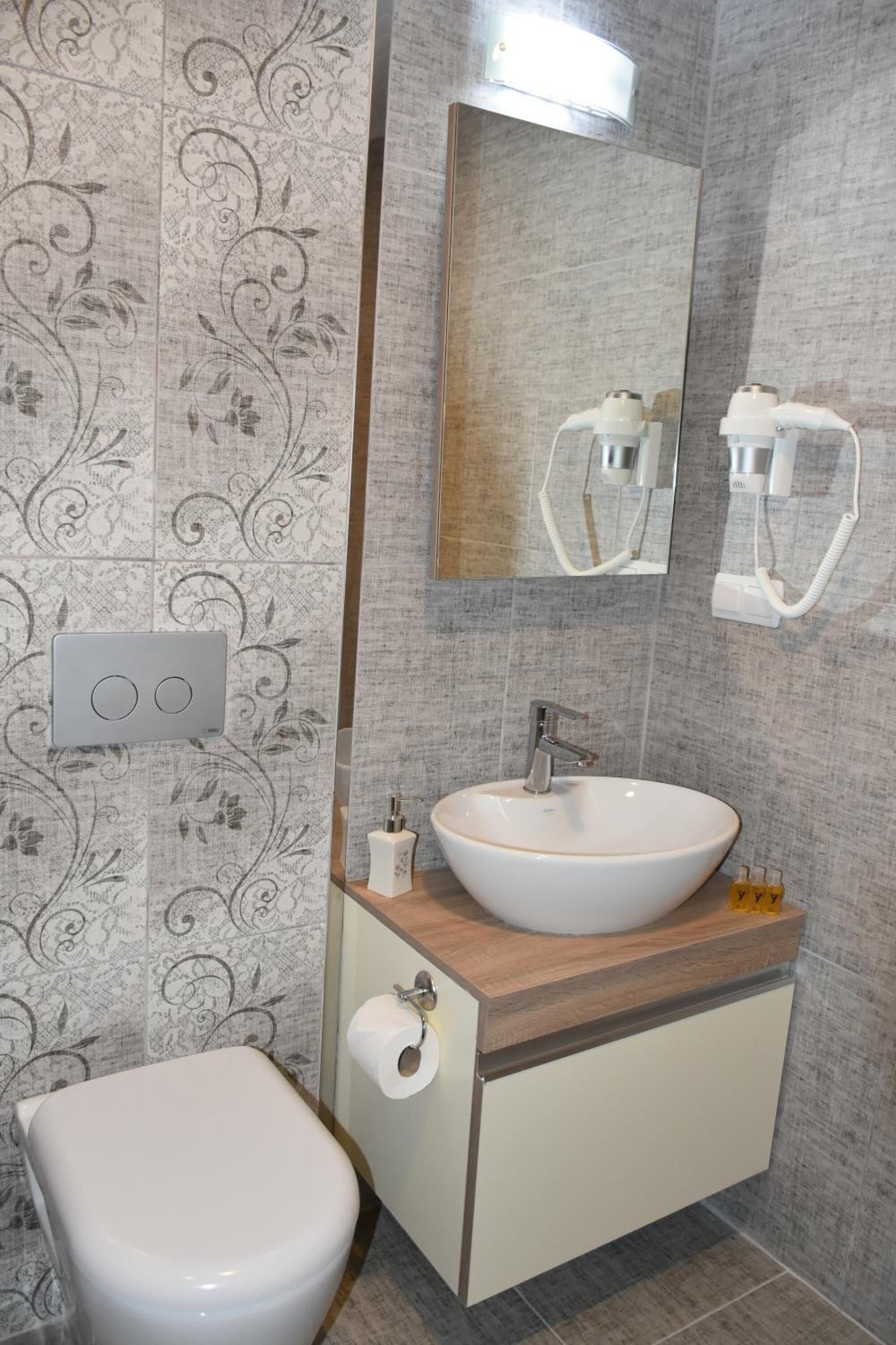 Une salle de bain comprenant des toilettes, un lavabo avec un miroir au-dessus, et un porte-serviettes.