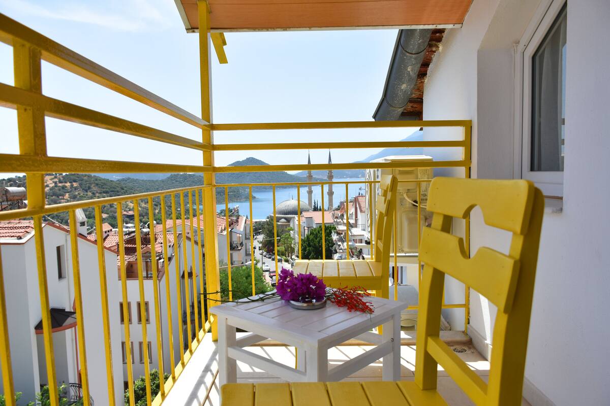A balcony with yellow railings, a white table, and a yellow chair.