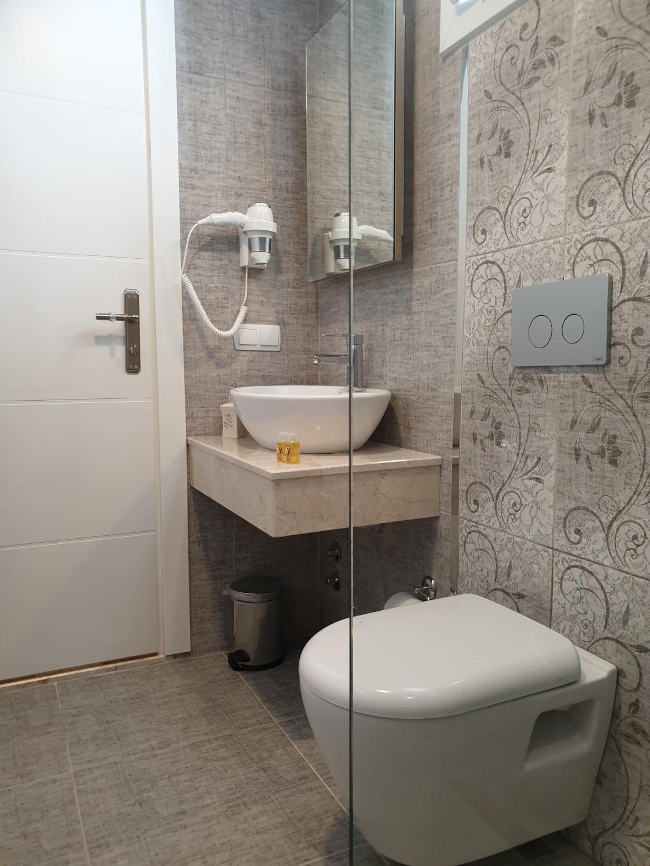 A bathroom with a white toilet, a white sink, and a glass shower enclosure.