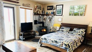 Een gezellige kamer met een bed, een televisie, een open haard en een houten tafel.