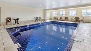 A large indoor swimming pool with tiled flooring, a pool ladder, and several seating areas with chairs and tables. - Comfort Inn & Suites Michigan City South (Michigan City)