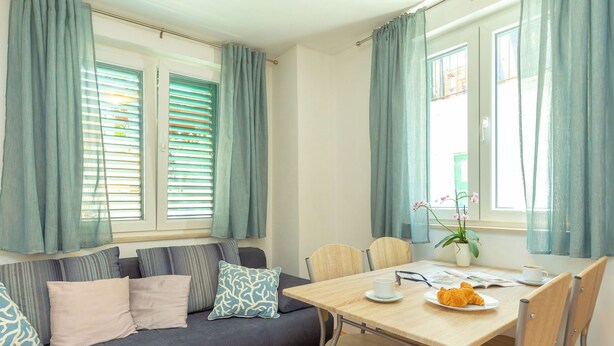 Una sala de estar acogedora con un sofá, una mesa de comedor y una planta en maceta.