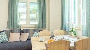 Una habitación acogedora con sofá, mesa de comedor y ventana con cortinas.
