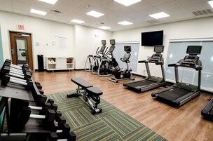 Un gimnasio con cintas de correr, elípticas y mancuernas.