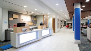 A modern hotel reception area with a reception desk, check-in counter, and a waiting area with chairs and tables. - Holiday Inn Express & Suites Taylor by IHG (Taylor)