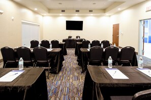 A conference room with rows of tables and chairs, water bottles on tables, and a flat-screen TV on the wall. - Holiday Inn Express & Suites Taylor by IHG (Taylor)