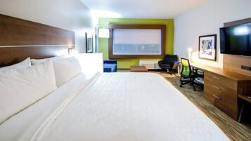 Quarto de hotel com uma cama grande, uma escrivaninha com cadeira, televisão e janela.