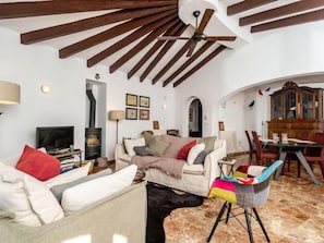 Uma sala de estar aconchegante com lareira, um sofá, uma TV e uma área de jantar com mesa e cadeiras.