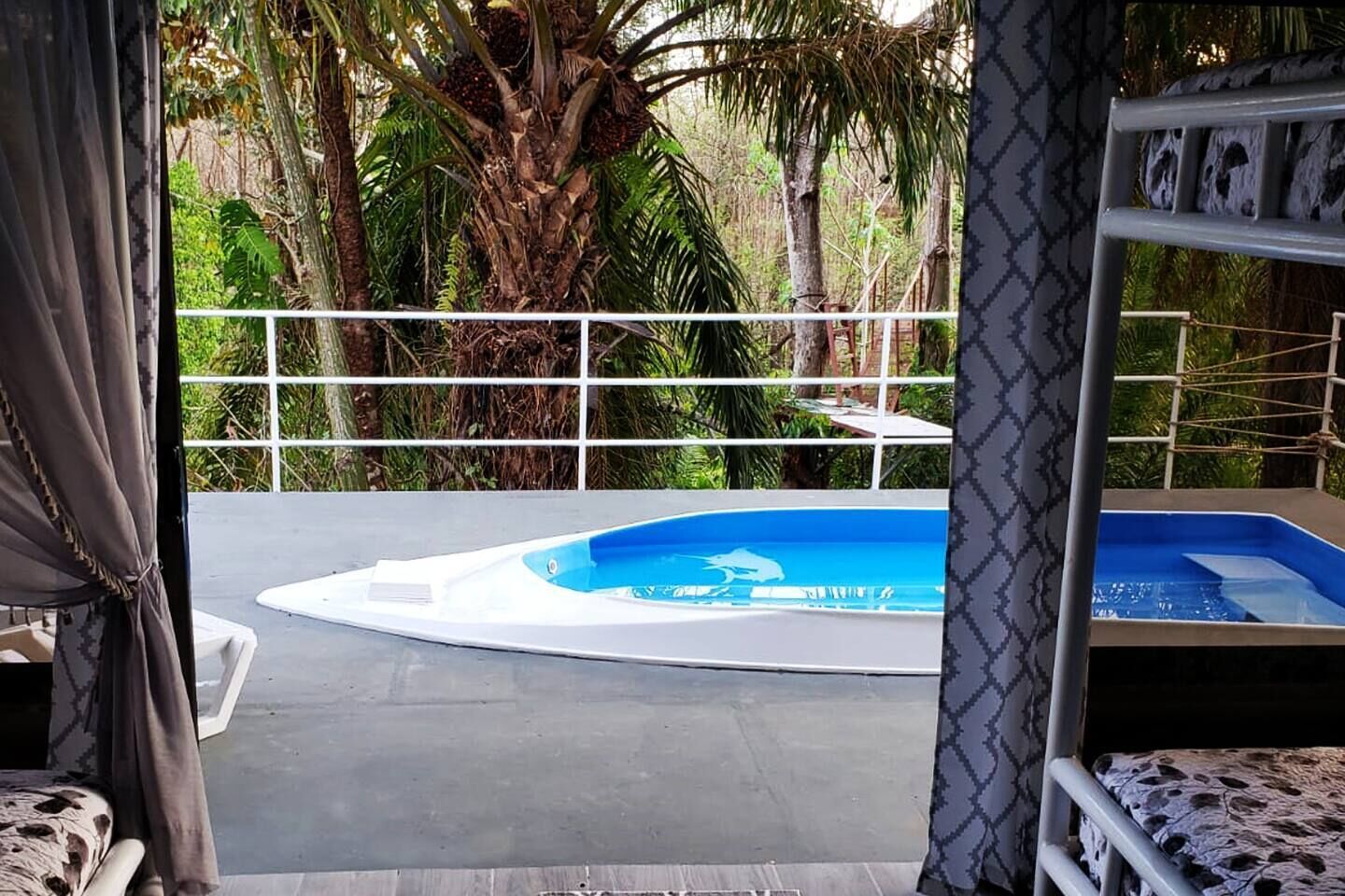 A circular pool with a blue center, surrounded by a white deck and a white railing.