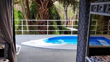 A circular pool with a blue center, surrounded by a white deck and a white railing.