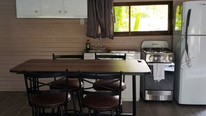 A compact kitchen with a dining table, chairs, a stove, and a refrigerator. - Relaxing Luxury Jungle Escape in Quepos with Jacuzzi, Zipline, Pool and more (Parrita)