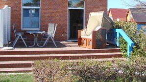 A brick building with a patio area featuring outdoor furniture and a blue staircase. - bright terrace apartment with beach chair in the old captain's house, max. 3 pers. (Prerow)