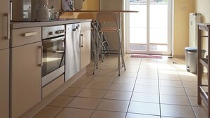 A kitchen with a large window, a stove, and a chair. - bright terrace apartment with beach chair in the old captain's house, max. 3 pers. (Prerow)