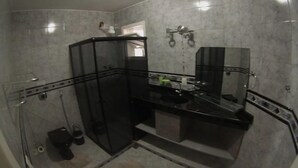 A modern bathroom with a glass shower enclosure, a black countertop, and a mirror. - Pousada Belo Horizonte (Macaé)