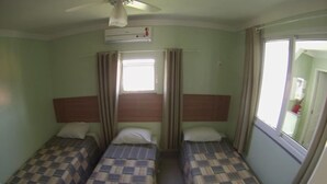 A small room with two single beds, a ceiling fan, an air conditioning unit, and a window with curtains. - Pousada Belo Horizonte (Macaé)