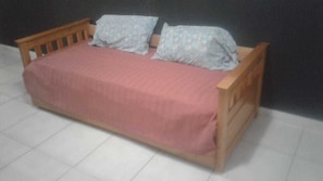 A single bed with a wooden frame and a pink bedspread. - Zona Peatonal Central Apartment Mendoza City (Mendoza)