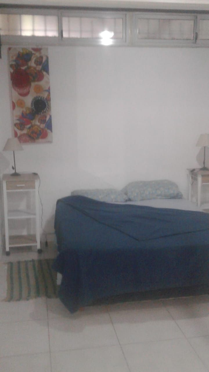 Un dormitorio con cama, mesita de noche, lámpara y un adorno en la pared.