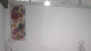 A bedroom with a bed, two nightstands, a lamp on each, and a colorful wall decoration. - Zona Peatonal Central Apartment Mendoza City (Mendoza)