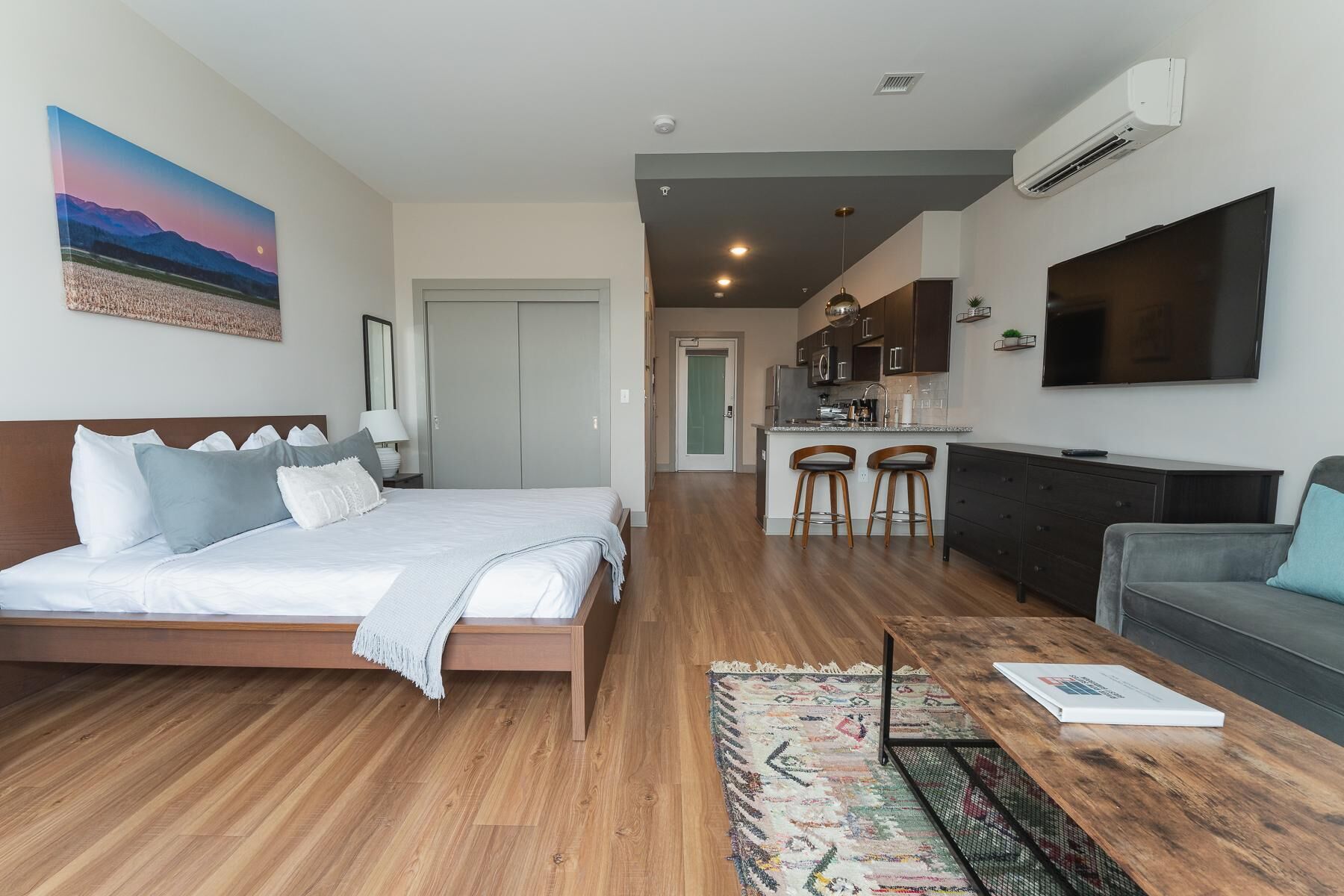 Une chambre d’hôtel moderne équipée d’un lit, d’un canapé, d’une table basse et d’un coin cuisine avec un téléviseur.