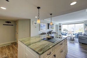 A modern kitchen with a marble countertop, wooden cabinets, and pendant lighting.