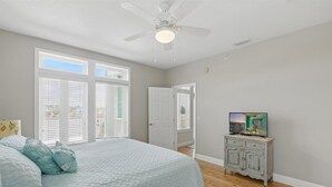 A bedroom with a bed, a ceiling fan, a TV on a dresser, and a door leading to another room. - Rivers Edge Condo #1A, Bldg 2- PRIVATE DOCK with ASSIGNED BOAT SLIP (Steinhatchee)