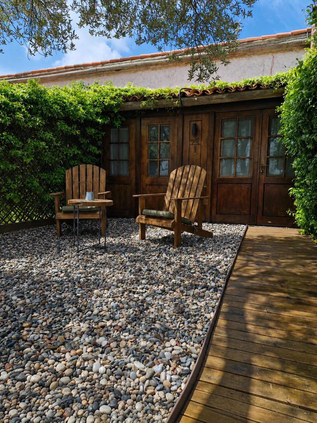 Un patio con dos sillas Adirondack de madera, una mesita y una terraza de madera.