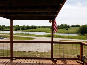 En træterrasse med udsigt over en flod, græsmarker og et amerikansk flag.