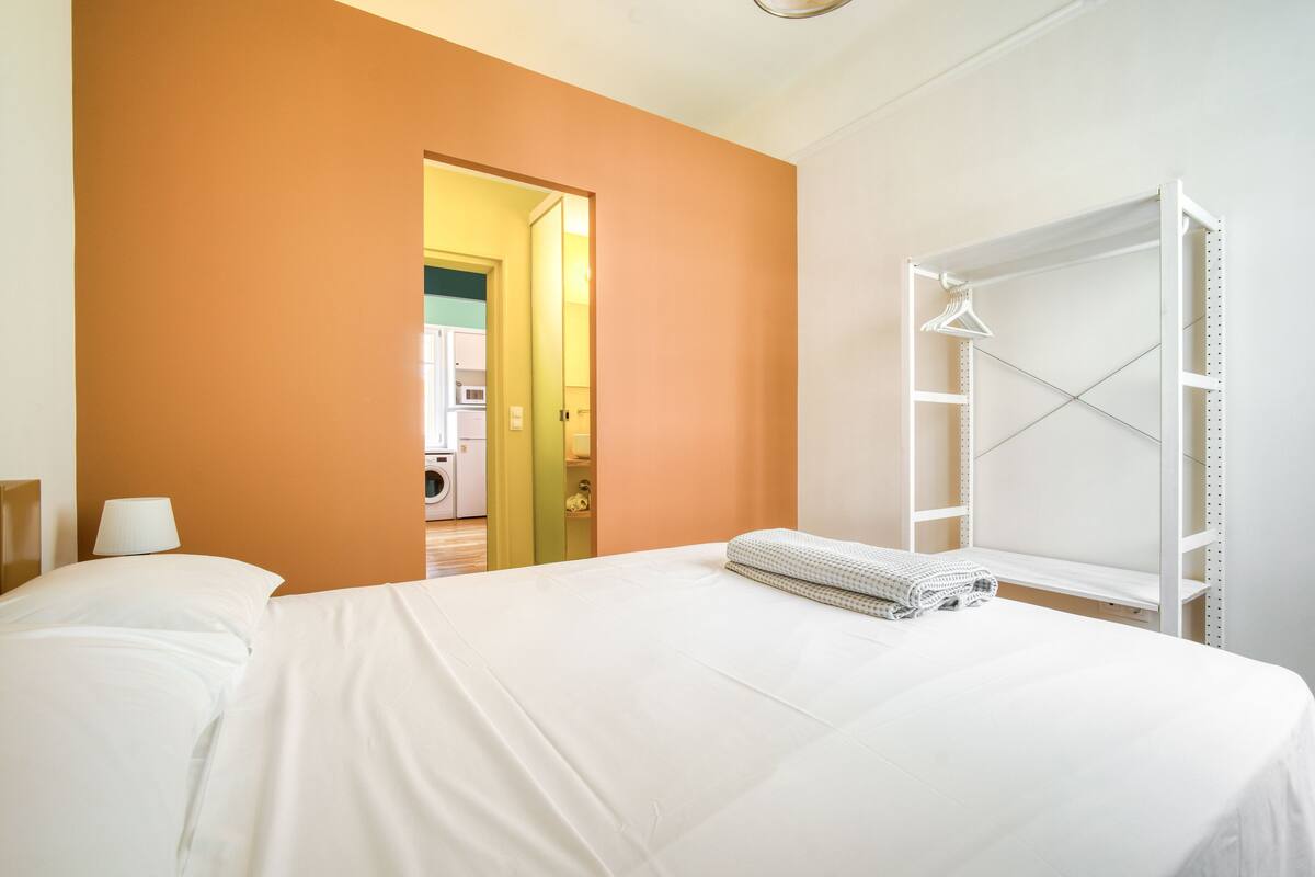 A hotel room with a bed, a wardrobe, and a bathroom visible through an open door.