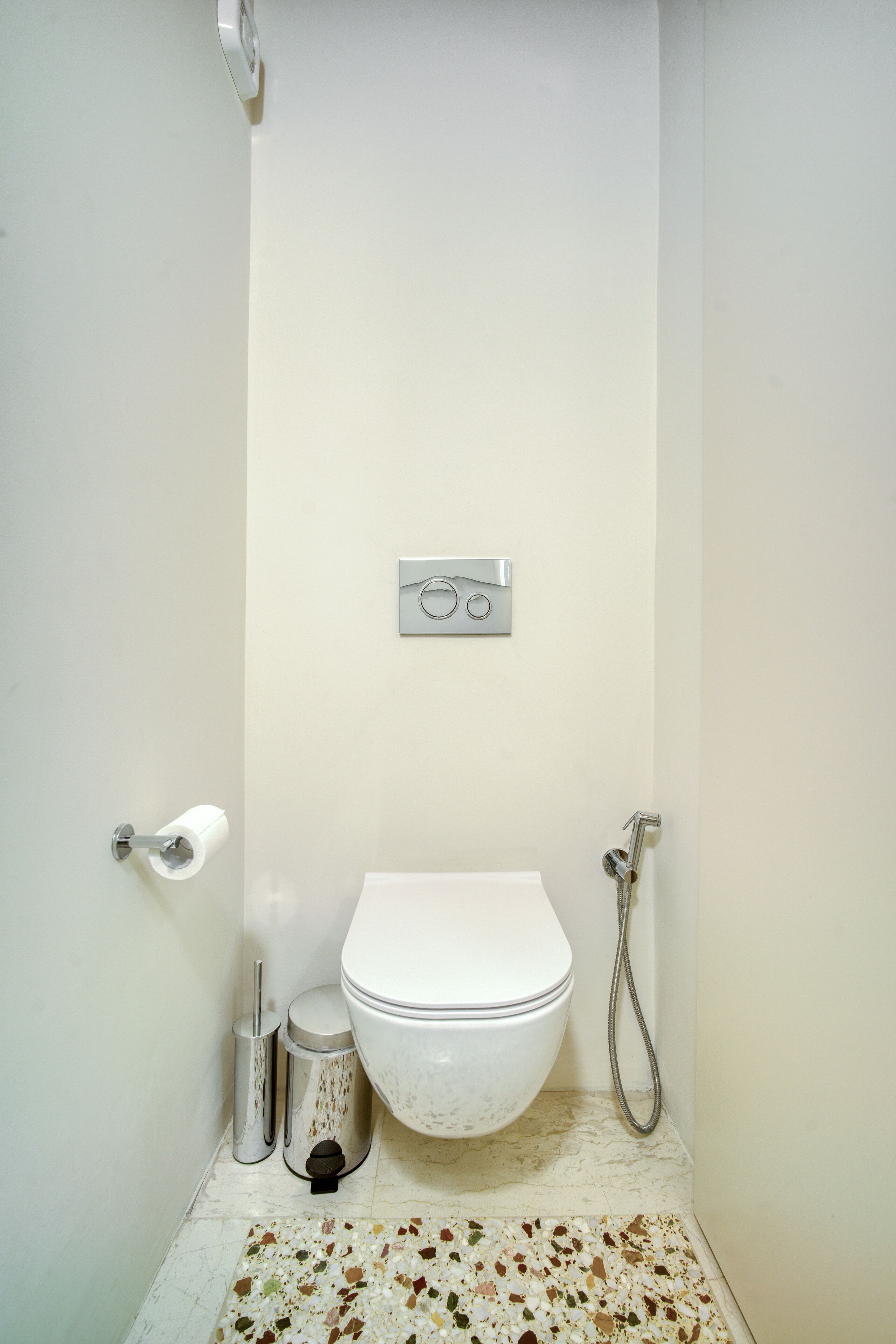 A small, compact bathroom with a toilet, bidet, and a wall-mounted control panel.
